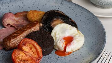 A plate of breakfast food including sausages, eggs, and tomatoes.