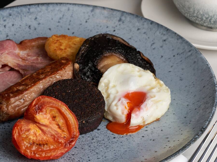 A plate of breakfast food including sausages, eggs, and tomatoes.