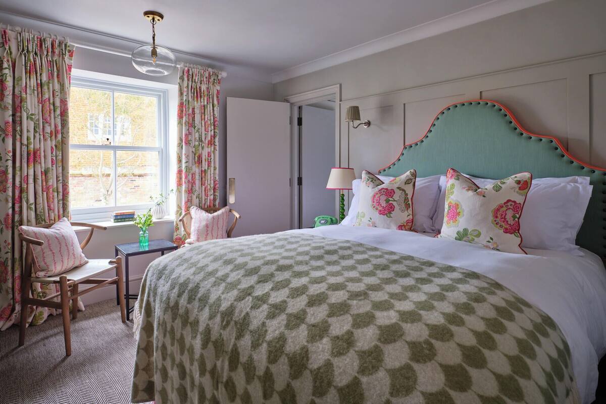 A bedroom with a bed, a chair, a table, and curtains.