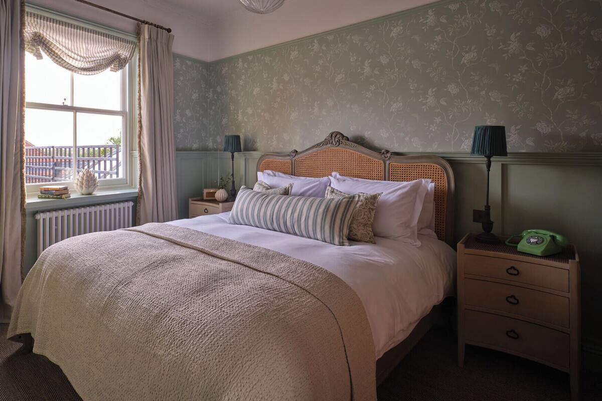 A bedroom with a bed, nightstands, a lamp, and a telephone.
