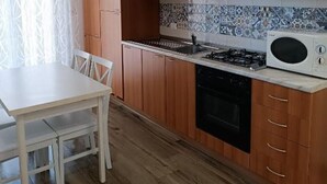 A kitchen with wooden cabinets, a white countertop, a stove, and a microwave.