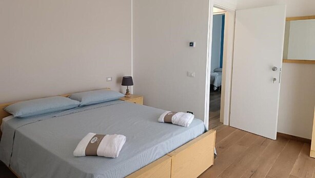 A bedroom with a bed, a nightstand, and a door leading to another room.