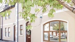 A building with a beige facade, a large arched window, and a door with a hanging wreath. - Owen Tucker View House (Ardara)