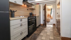 A modern kitchen with a built-in oven, a refrigerator, and wooden cabinetry. - Wether Fell View (Hawes)