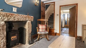 A cozy living room with a stone fireplace, a wooden chair, and a staircase leading to another room. - Wether Fell View (Hawes)