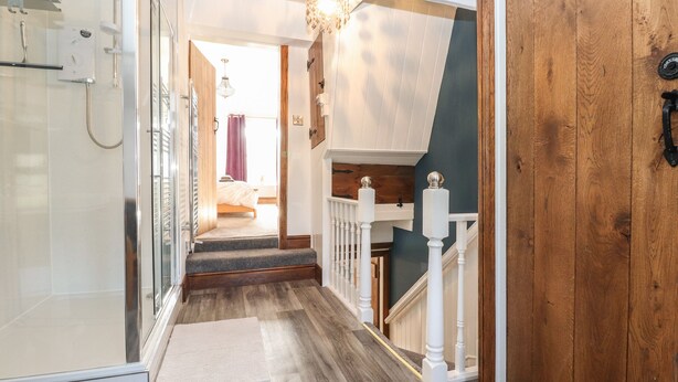 A hallway with a wooden floor, white railing, and a door on the right. - Wether Fell View (Hawes)