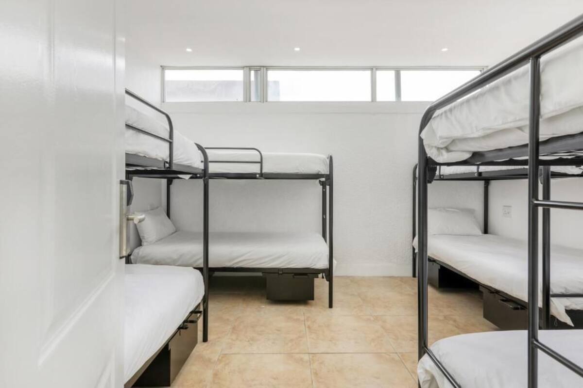 A dormitory room with bunk beds, a window, and a tiled floor.
