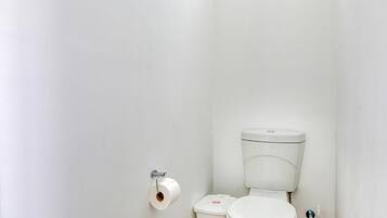 A white toilet with a flush handle and a paper towel holder on the wall.