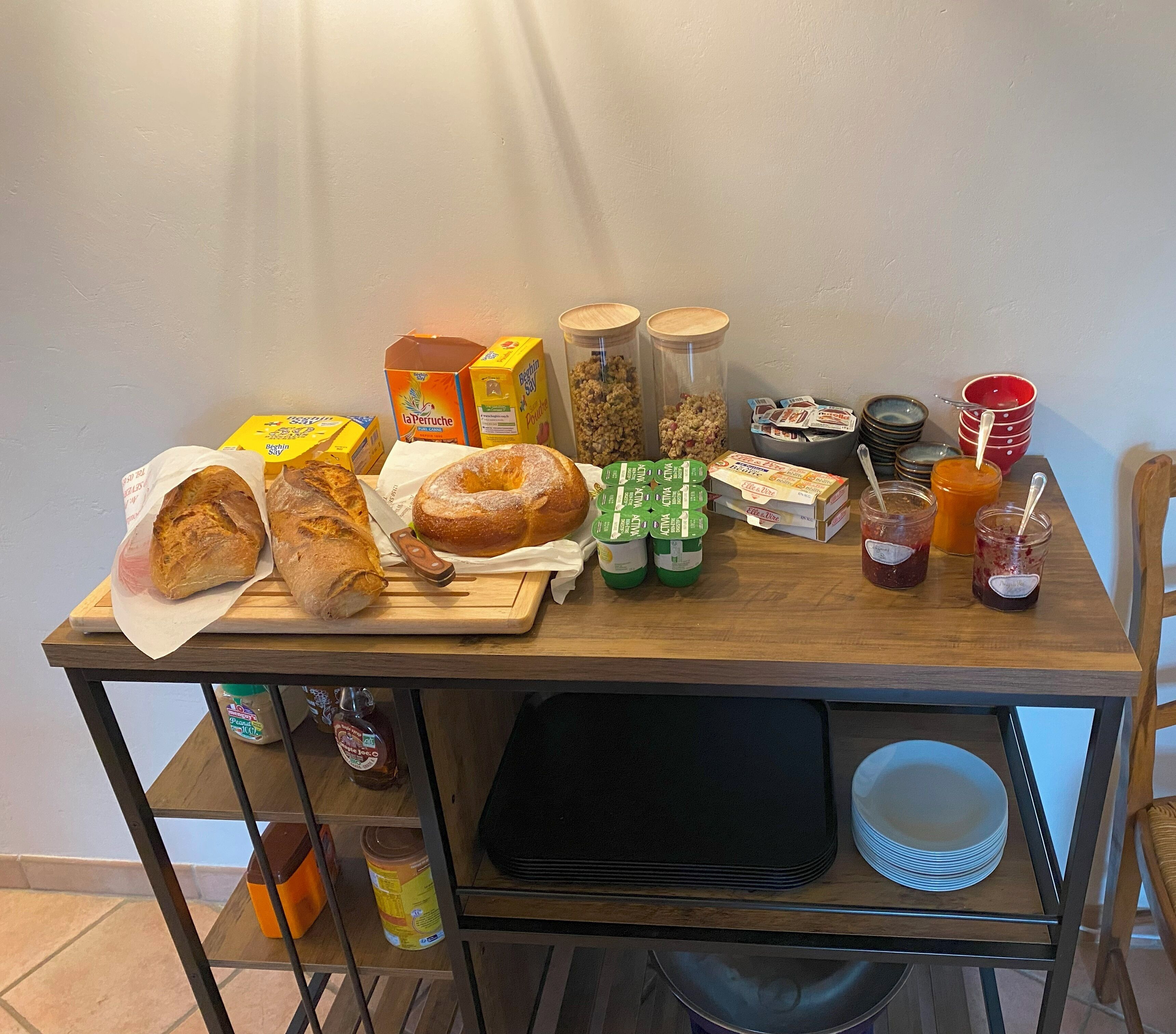 Una mesa de madera con diversos alimentos, como pan, tarros de crema de cacahuete y aderezos.