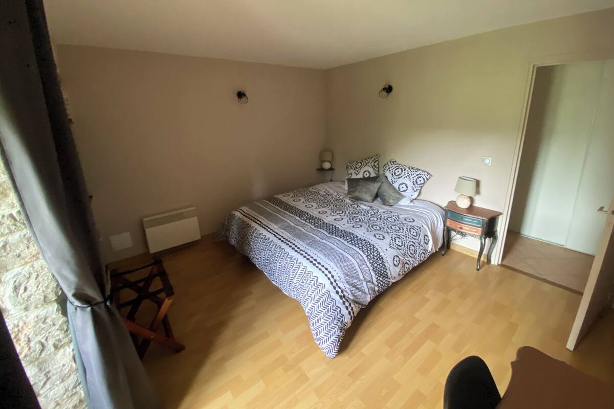 Une chambre à coucher avec un lit, des tables de chevet, un radiateur et une porte.