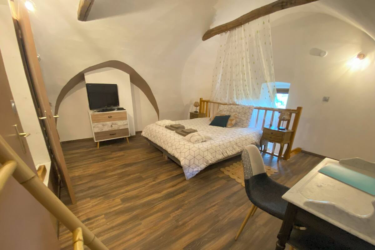 Une chambre à coucher comprenant un lit, une table de chevet, une chaise et un téléviseur.