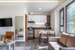 A modern kitchen with a built-in microwave, stainless steel refrigerator, and wooden cabinets. There is a dining area with a table and chairs, and a large window providing natural light. - Scape by Villa John (Laklouk)