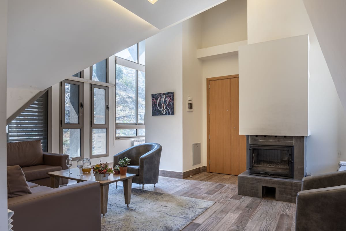 A modern living room with a fireplace, a sofa, a coffee table, and a chair.
