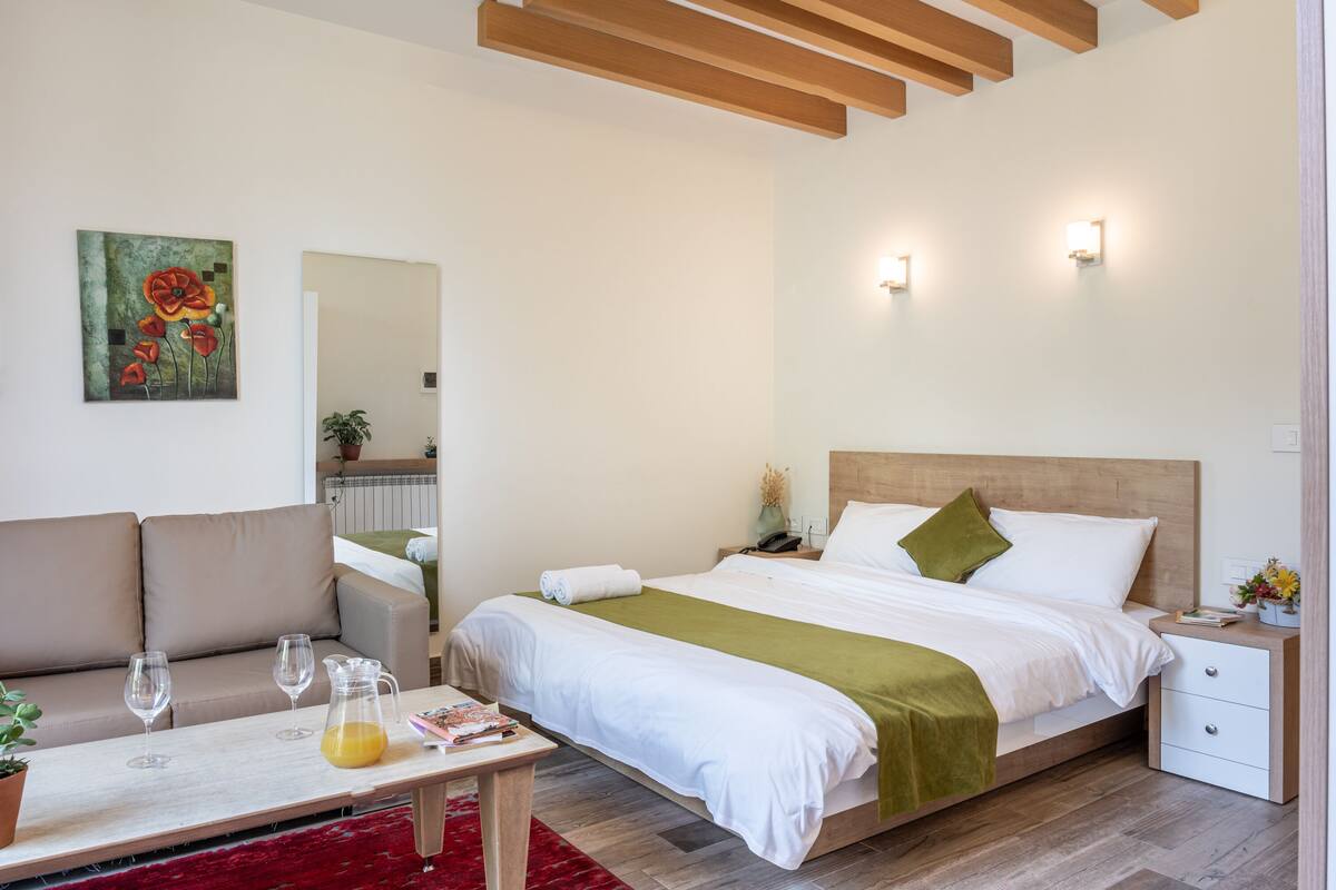 A modern bedroom with a bed, bedside tables, a sofa, and a coffee table.