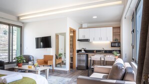 Ein modernes Hotelzimmer mit Bett, Sitzecke, Küchenzeile und Fernseher.