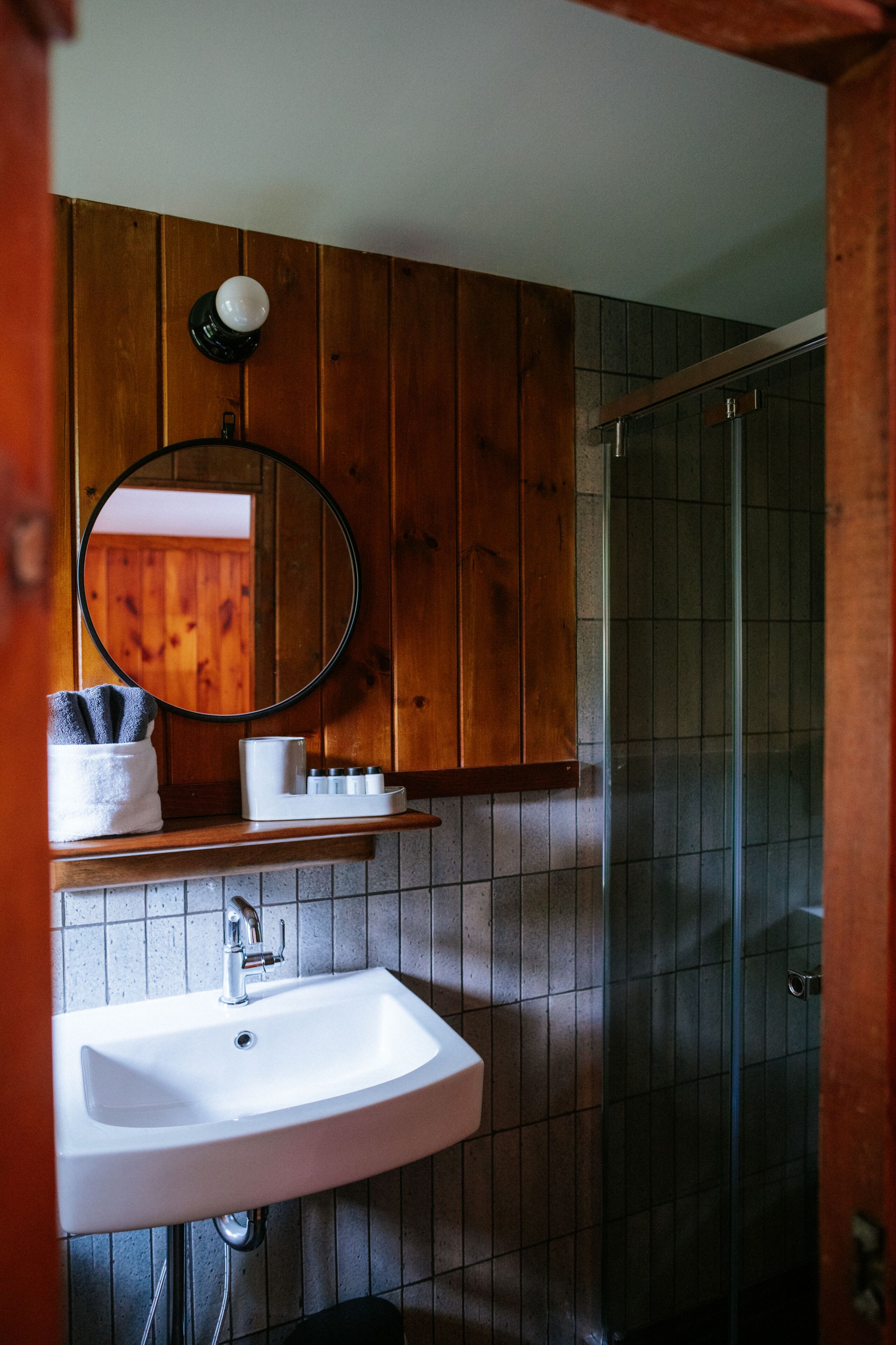A bathroom with a white sink, a mirror, and a glass shower enclosure.