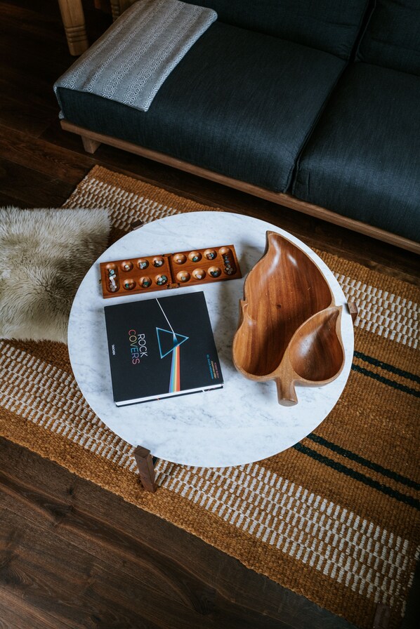 A round table with a book titled "Rock Covers," a wooden bowl, and a set of keys.