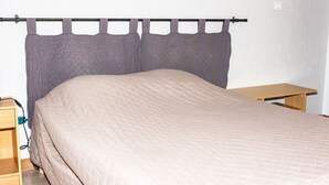 Una cama individual con cabecera, una mesita de noche y un enchufe en la pared.