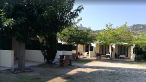 Un patio con mobiliario exterior, un árbol y un edificio con techo de tejas.