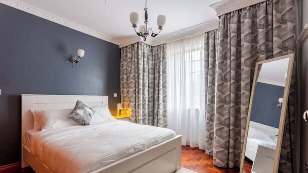 A bedroom with a large bed, a nightstand, a mirror, and a chandelier.