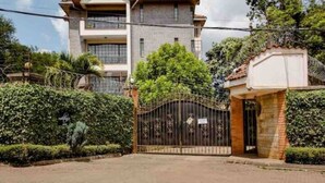 A gated residential building with a two-story structure, a gated entrance, and a well-maintained garden.