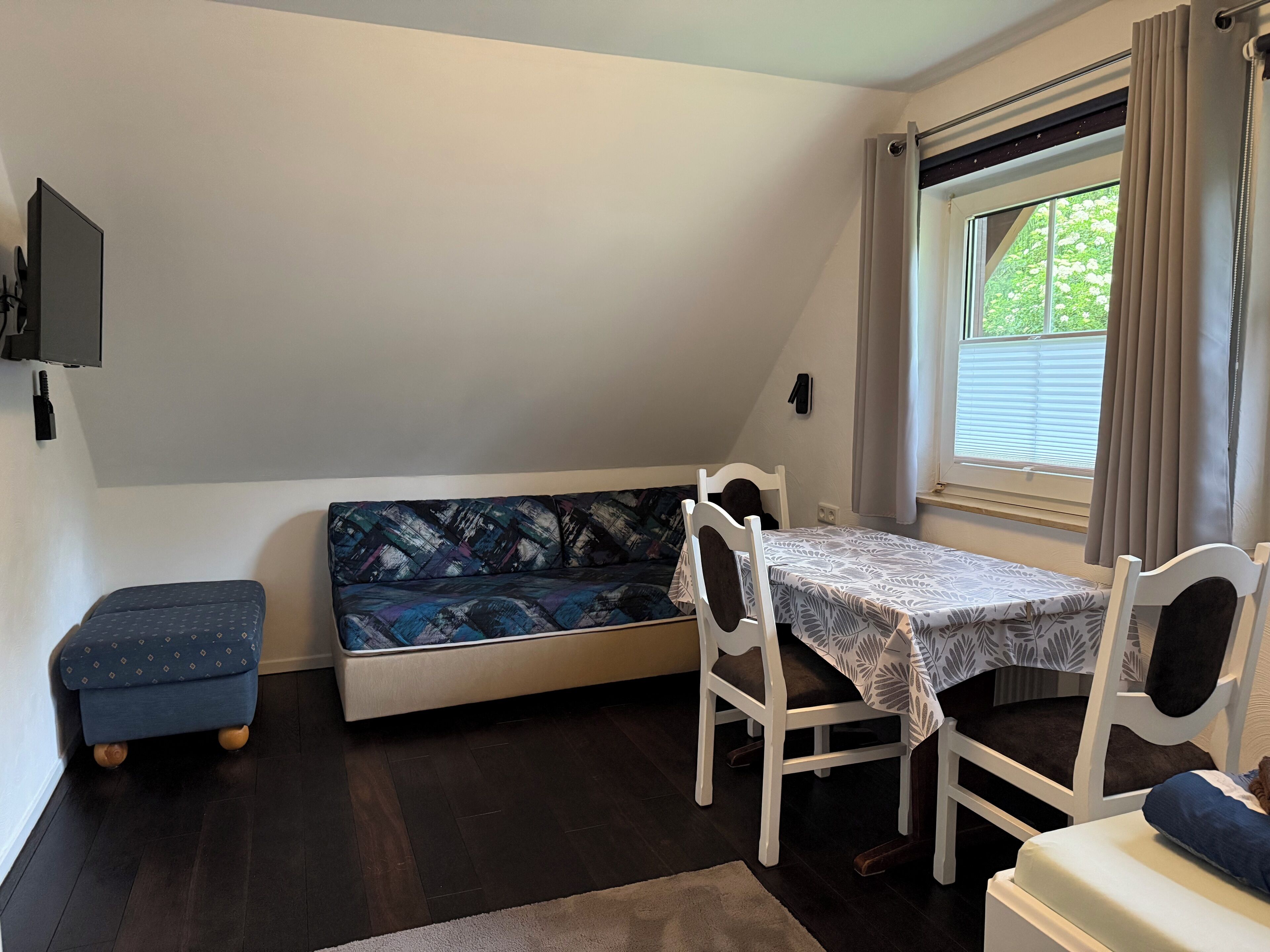 A small room with a sofa, a table, a chair, and a window with curtains.