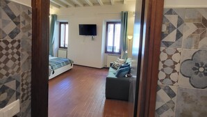A spacious room with a wooden ceiling, a bed, a sofa, and a TV mounted on the wall. - 40 m2 studio in the center of Brescia, 90 m from parking, no ZCL (Brescia)