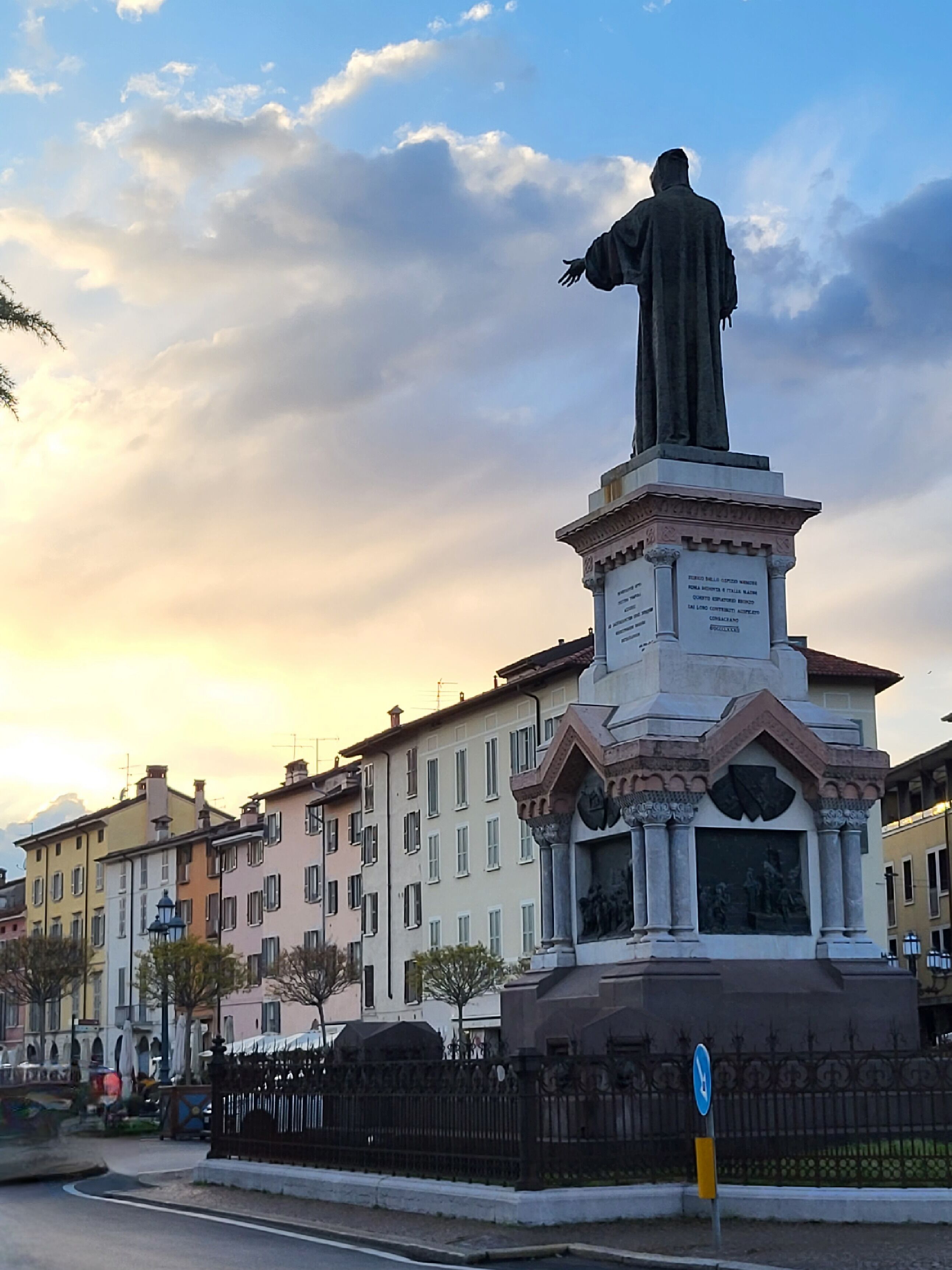 Une statue sur un piédestal, dans un espace public, entourée d’immeubles.