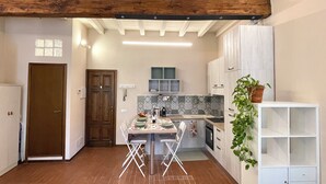 A kitchen with a dining table, chairs, a potted plant, and cabinets. - 40 m2 studio in the center of Brescia, 90 m from parking, no ZCL (Brescia)