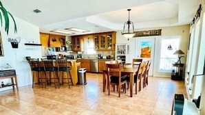A spacious kitchen with a dining area, a bar, and a large window providing natural light. - Wake Up to a Beautiful View! 3bdrm, 2 bath. Private Fishing Pier. (Port Mansfield)