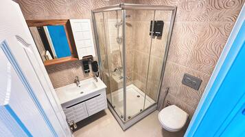Une salle de bain avec une douche à parois de verre, un lavabo et des toilettes.