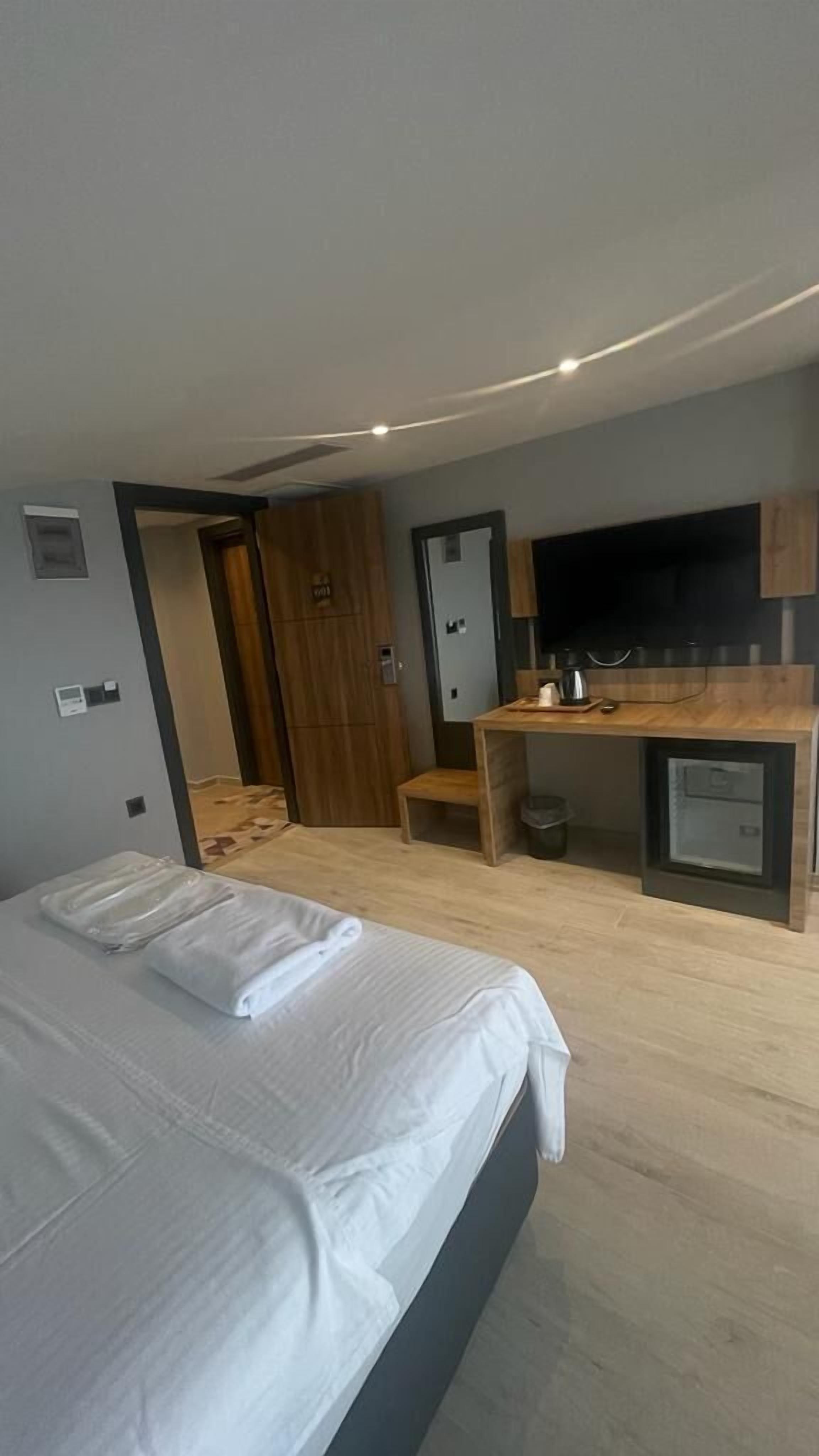 Een hotelkamer met een bed, bureau, televisie en kledingkast.
