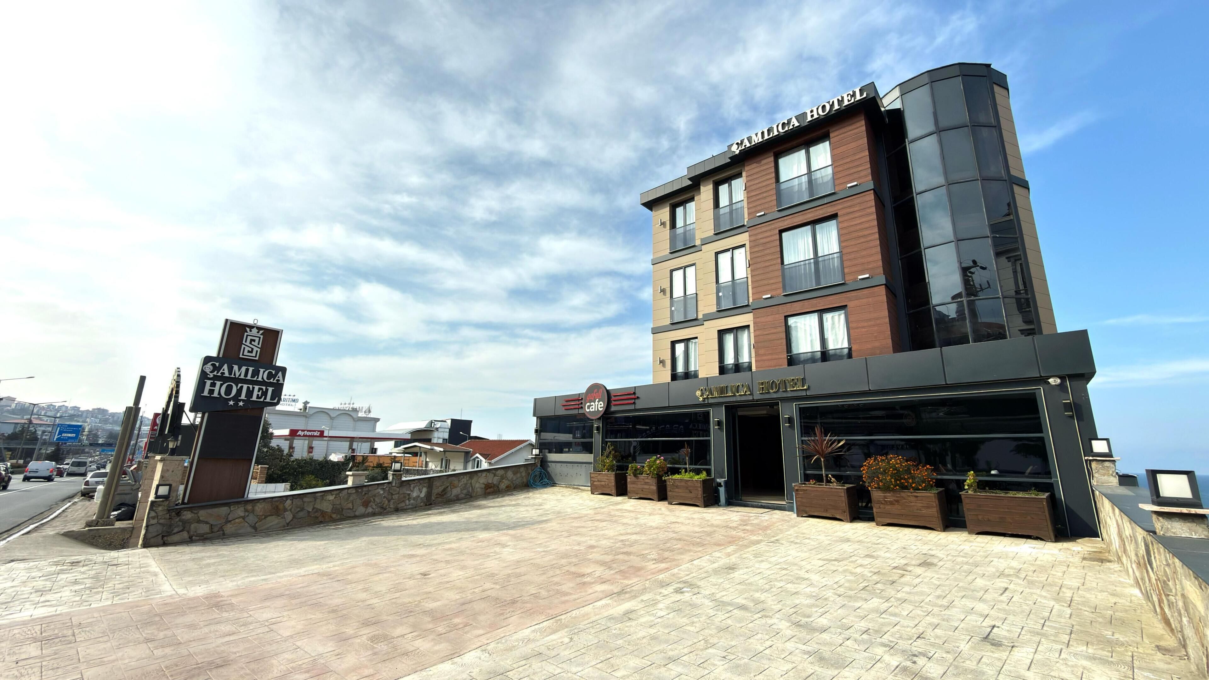 A modern hotel with a cafe, stone facade, and a clear sky.