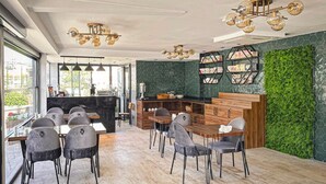 Un comedor moderno con una mesa y sillas de madera, una pared verde con jardín vertical y un techo con un diseño de lámpara único.