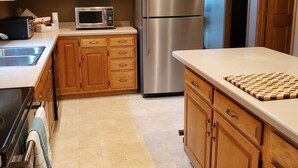 Una cucina moderna con mobili in legno, elettrodomestici in acciaio inossidabile e pavimento piastrellato.