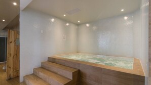 Een spa-ruimte met een houten trap die leidt naar een zone met een jacuzzi.