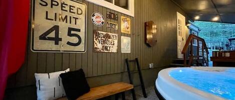 A room with a speed limit sign, a bench, a hot tub, and various wall decorations.