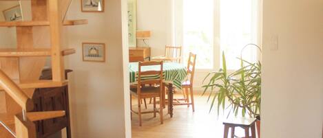 A wooden staircase leading to a second floor, a dining area with a table and chairs, and a hanging light fixture.