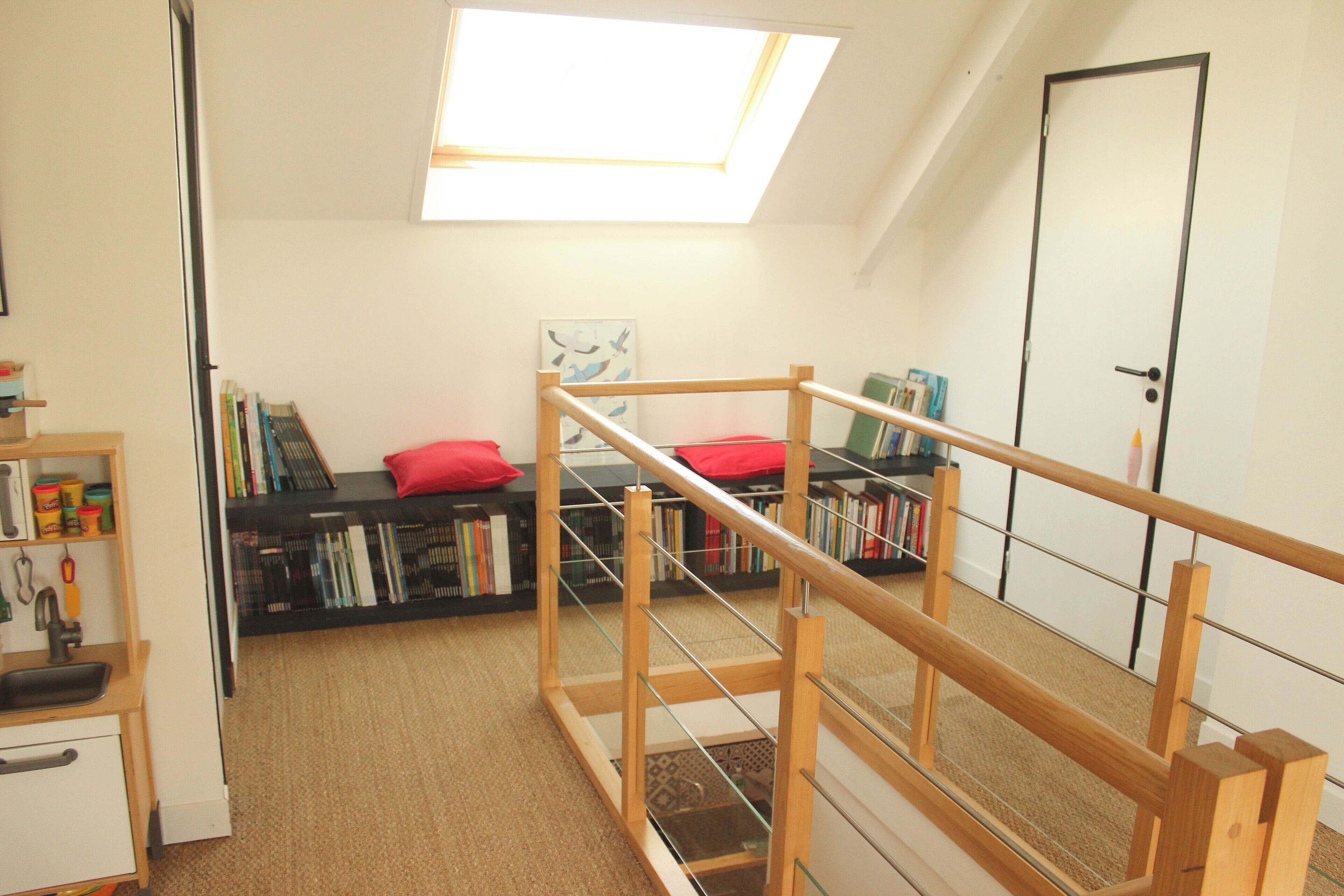 A room with a skylight, a bookshelf, a small desk, and a door.