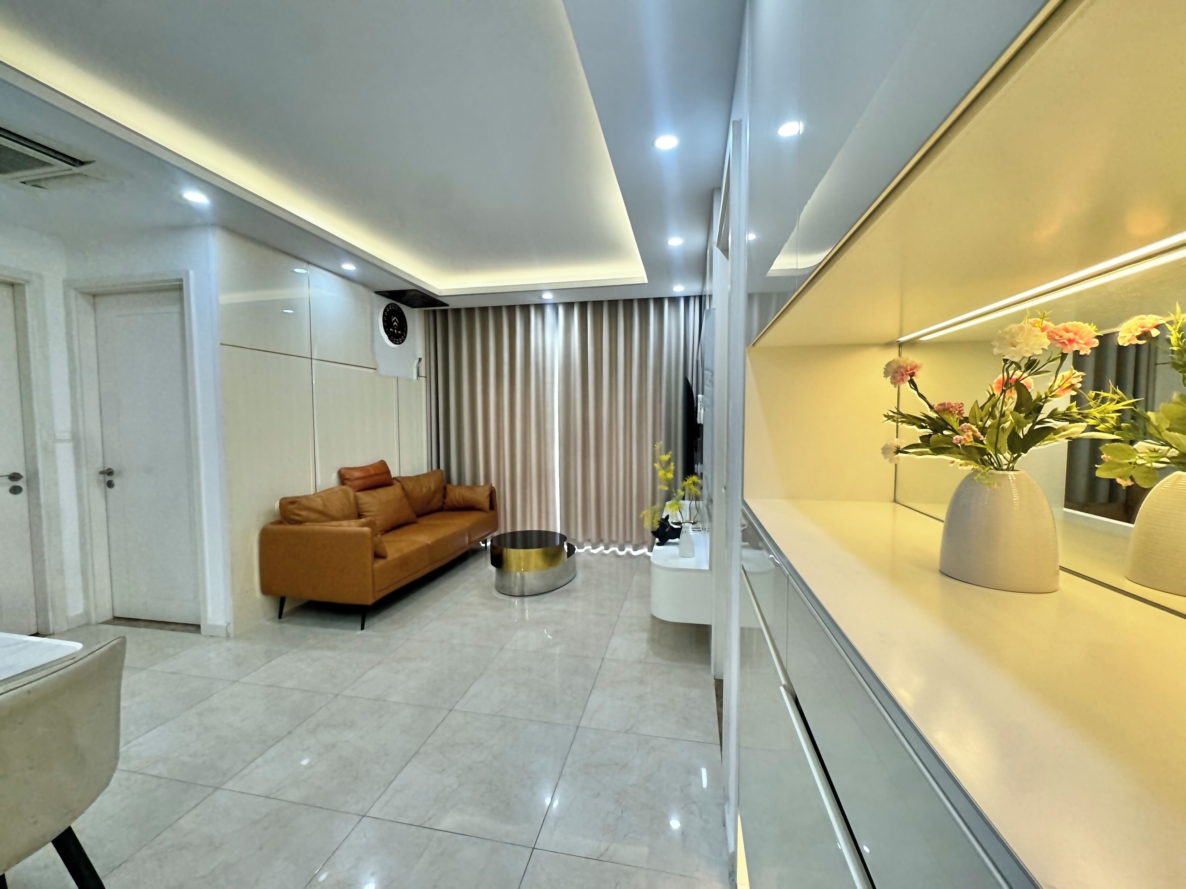 A modern living room with a sofa, a coffee table, and a vase of flowers.