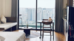 A modern hotel room with a balcony, a sofa, a dining table, and a TV. - Vinhome D'capitale Service Apartment - Mikage Housing (Hanoi)