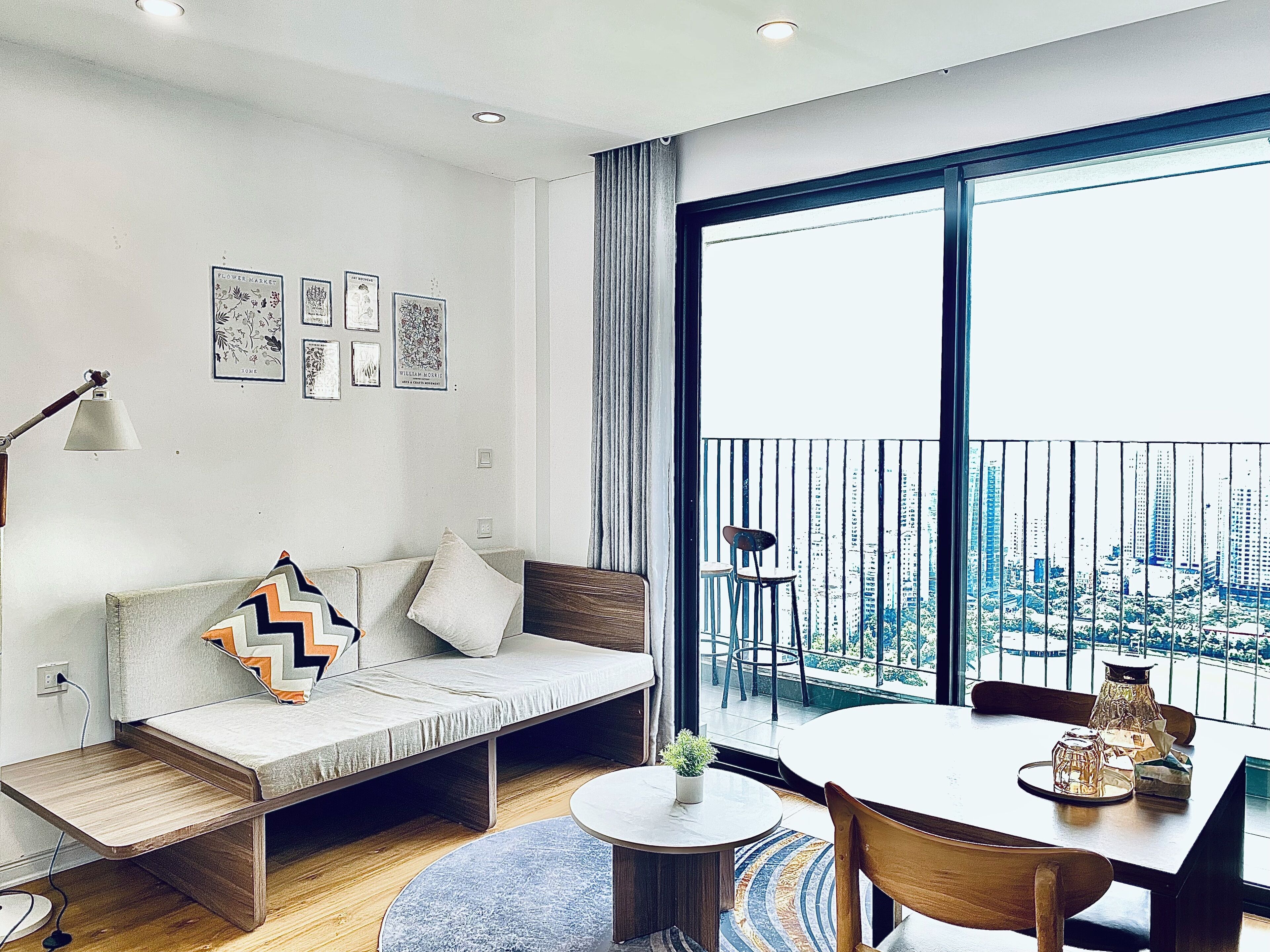 A modern living room with a sofa, a small table, and a balcony with a city view.