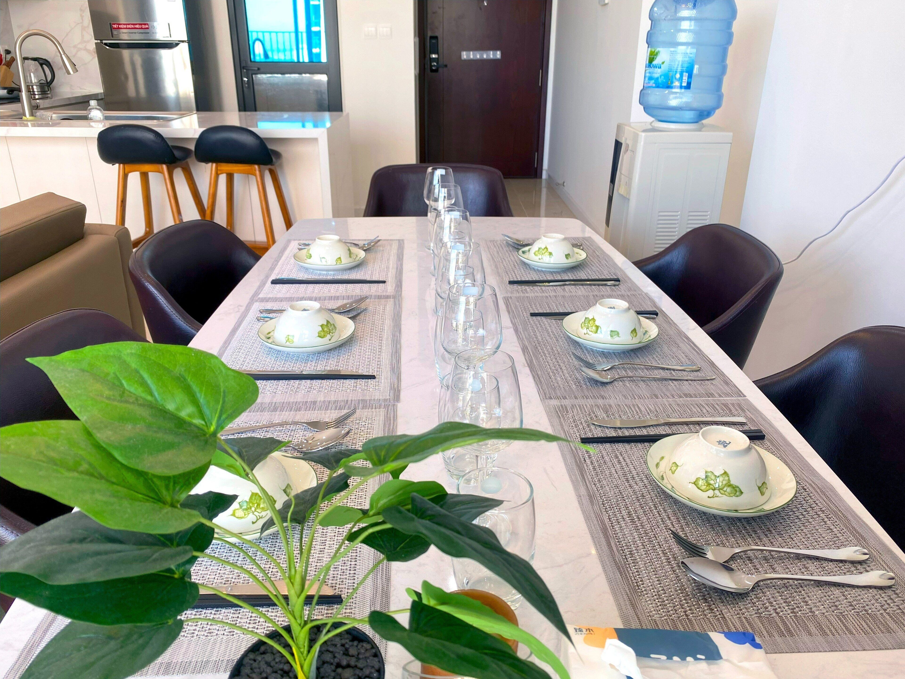 A dining table set with plates, glasses, and cutlery, surrounded by chairs.