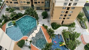 A residential building with a swimming pool, palm trees, and a children's play area. - Vinhome D'capitale Service Apartment - Mikage Housing (Hanoi)