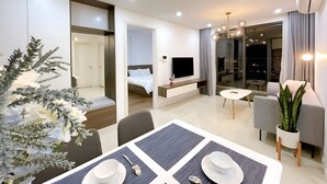 A modern hotel room with a dining area, a bed, a TV, and a balcony with a city view. - Vinhome D'capitale Service Apartment - Mikage Housing (Hanoi)