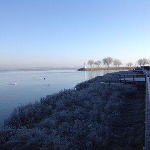 A frozen river with a bridge and a lighthouse in the distance.