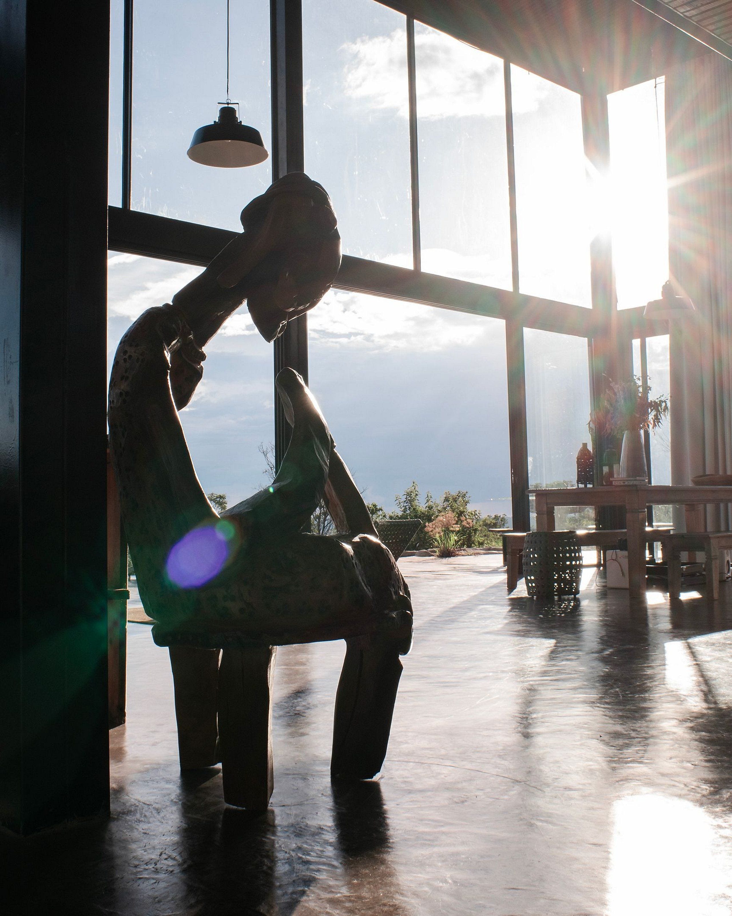 A person sitting by a window with a view of the sky and a plant on a table.