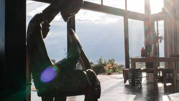 A person sitting by a window with a view of the sky and a plant on a table.
