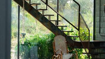 Una silla de mimbre debajo de una escalera, con vistas a la vegetación.