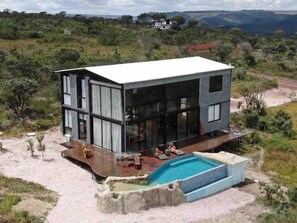 A modern two-story house with a large glass facade, a swimming pool, and a deck area. - CASA ÔNIX (Alto Paraíso de Goiás)